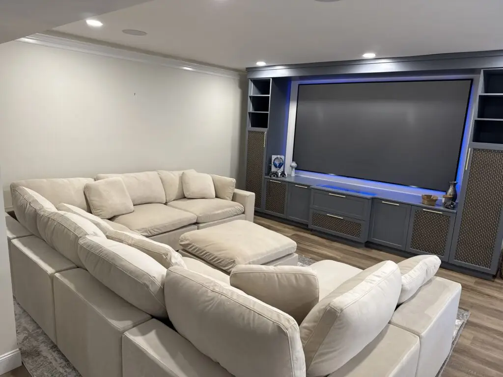 Cream sectional sofa and home theater wall unit with large screen assembled in a finished basement