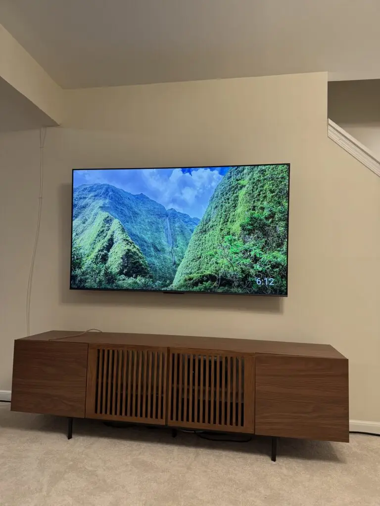 Flat-screen TV wall-mounted above a mid-century wood media console