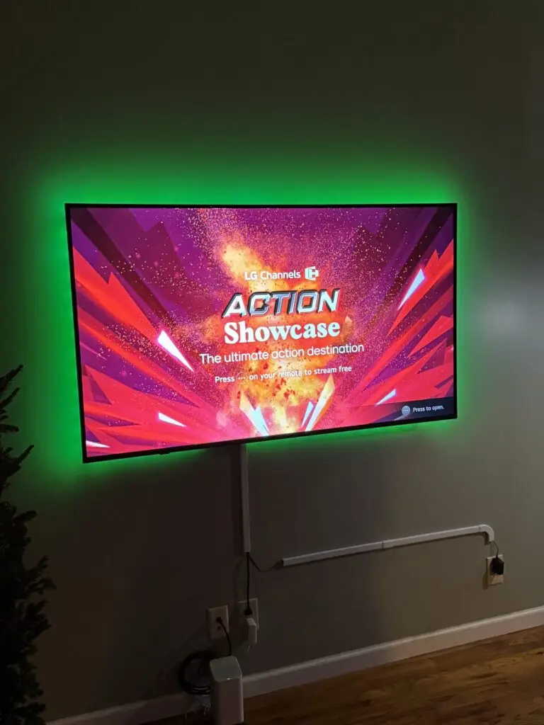 Wall-mounted TV with green LED backlighting installed in a dark room
